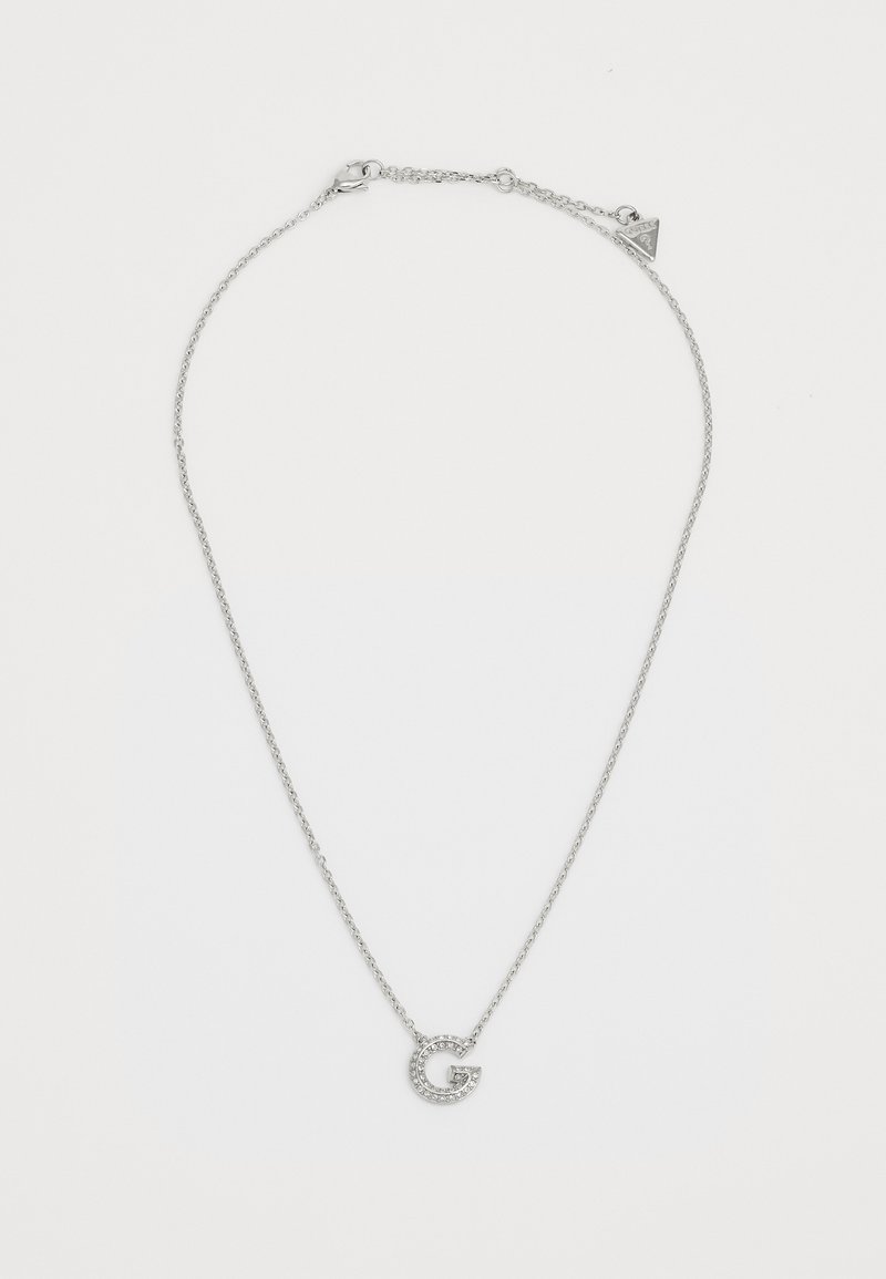 Collar de plata que presenta una cadena delicada y un colgante circular decorado con pequeñas piedras transparentes, con forma de la letra "G."