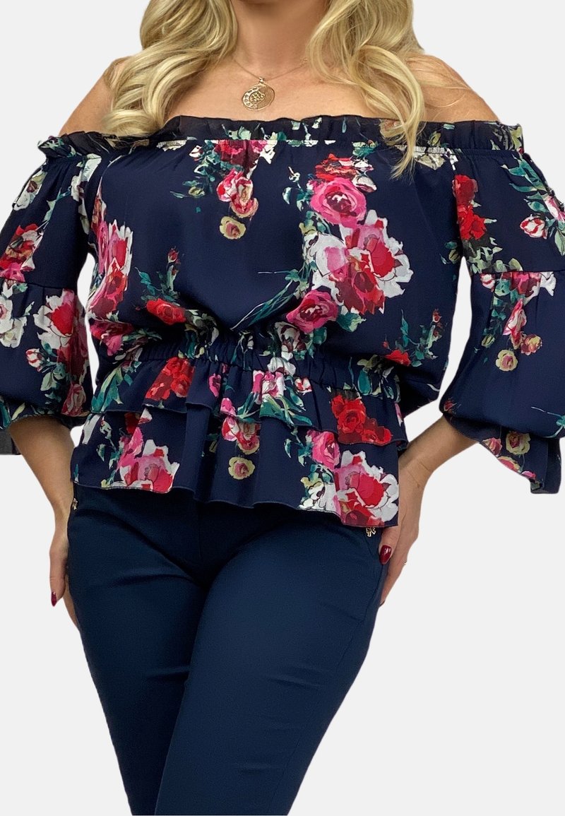 Haut floral navy à épaules dénudées avec un ourlet volanté, une taille élastique et des manches évasées, arborant un mélange de motifs de fleurs roses, rouges et vertes.