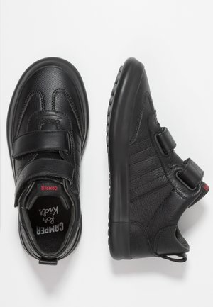 Schwarze Kindersneaker mit doppelten Klettverschlüssen, strukturiertem Leder und dicken Gummisohlen, von oben und von der Seite auf weißem Hintergrund gezeigt.