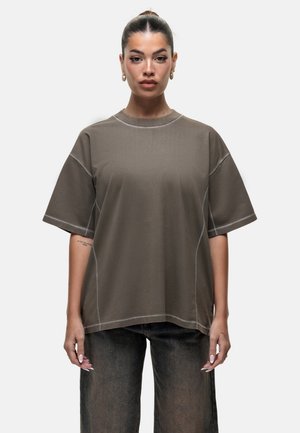 Bruine oversized t-shirt van zacht materiaal, met een ronde hals, korte mouwen en contrasterende stiksels langs de naden.