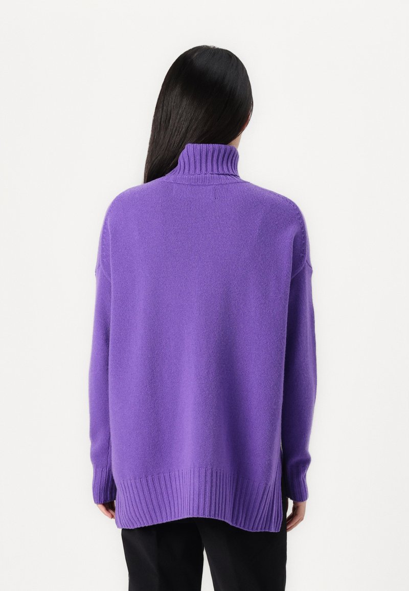 Übergroßer lila Strickpullover mit hohem Kragen, gerippten Bündchen und Saum. Glatte Textur, mit tiefen Schultern und lässiger Passform.