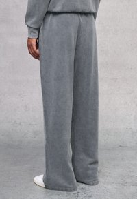 Grijze katoenmix wijde broek met een zachte textuur, voorzien van een elastische taille en een relaxte pasvorm, gecombineerd met witte sneakers.