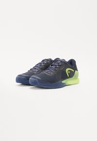 Chaussures de sport en maille marine avec une finition texturée, dotées d'accents et de lacets vert citron, ainsi qu'une semelle extérieure en caoutchouc robuste.