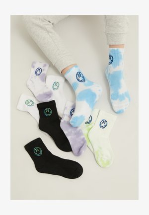 Chaussettes colorées dans différents styles : un dégradé bleu tie-dye, blanches avec des accents verts, noires et violettes. Chacune arbore un logo graphique avec un visage souriant.