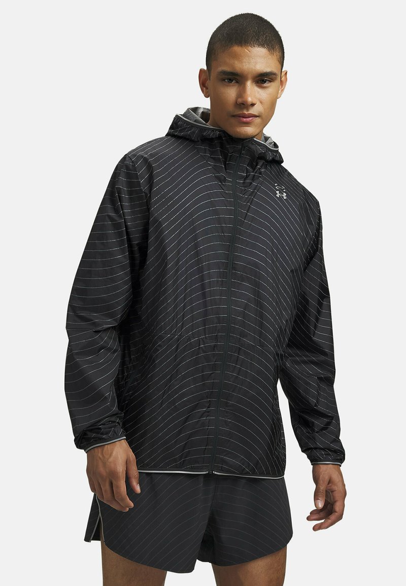 Čierna ľahká bunda s bielymi horizontálnymi pruhmi, kapucňou a zipsovým zatváraním. Má uvoľnený strih a jemnú textúru.