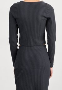 Svart ribbad långärmad crop top med rund halsringning, som har en figurnära design och texturerad tyg, tillsammans med en matchande ribbad kjol.