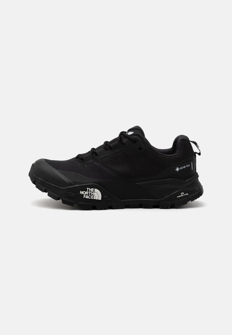 Zapato de senderismo negro con parte superior de malla texturizada, etiqueta GORE-TEX, suela de goma resistente y detalle de logo en el lateral. Diseño ligero.
