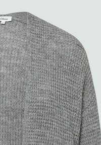 Grauer, gestrickter Cardigan mit offenem Design. Strukturiertes Material zeigt ein Muster aus kleinen, erhabenen Details. Etikett sichtbar am Ausschnitt.