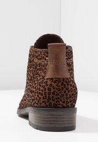 Stivale alla caviglia in suede marrone con un motivo a stampa leopardata. Presenta un'etichetta in pelle sul retro e un tacco di legno basso. Texture liscia.