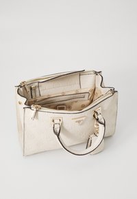 Borsa a tracolla bianca con texture, caratterizzata da una placca con logo in tonalità oro, chiusura con zip superiore e doppi manici con rifiniture nere. L'interno include diversi scomparti.