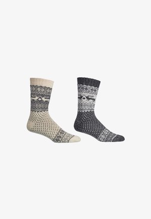 Paar gestrickter Wollsocken, eines in Beige und eines in Dunkelgrau, jeweils mit nordischen Mustern einschließlich Rentieren und geometrischen Designs.