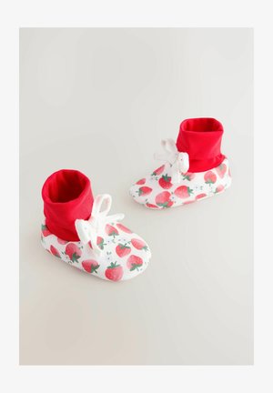Petit chaussons blancs avec bordure rouge à la cheville, ornés d'un motif de fraises et de petits nœuds blancs. Texture douce, design léger pour bébés.