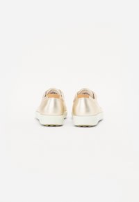 Metallic gold shoes with a smooth texture, rounded shape, and white soles. Features a minimalist design and leather accents at the heel.