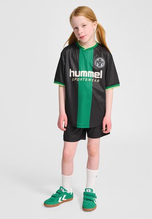 Zwart en groen gestreept sportshirt met logo en de tekst "hummel", gecombineerd met zwarte shorts en groene sneakers met witte accenten.