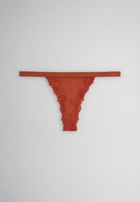 Rust-colored lace-trimmed thong underwear with a thin waistband laid flat on a light gray background.