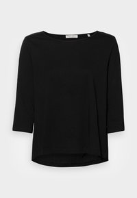 Sort top med trekvartærmer lavet af blød bomuld. Rund halsudskæring, afslappet pasform, længere ryg og subtile sideslids for bedre bevægelsesfrihed.