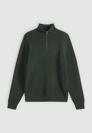 Camisola verde-escura canelada com gola alta e fecho de meio zip. Apresenta mangas compridas e corte ligeiramente folgado, realçando a textura e o trabalho artístico.