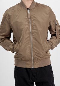 Giubbotto bomber in nylon marrone con chiusura frontale a zip, polsini e orlo a coste, tasche laterali e tasca con zip sulla manica sinistra.