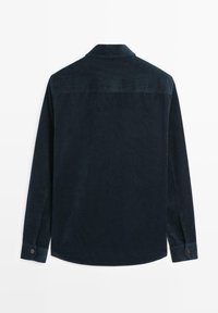 Camicia in corduroy verde scuro con colletto, maniche lunghe, polsini abbottonati e una texture a righe. La vista posteriore mette in evidenza una finitura liscia.