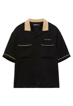 Musta lyhythihainen nappipaita, jossa on beige kaulus, beiget reunat taskuissa ja hihoissa sekä vasemmassa rinnassa kirjailtu "Pure Purpose".