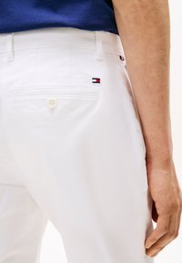 Άσπρο παντελόνι με πίσω τσέπη που φέρει μικρό κεντημένο λογότυπο σε κόκκινο, λευκό και μπλε. Λείο ύφασμα, απλός σχεδιασμός, κλασική εφαρμογή.