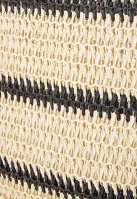 Vevd kurv med sammenflettede naturfibre, med et mønster i kremfarge og svart striper, som viser et teksturert og solid design.