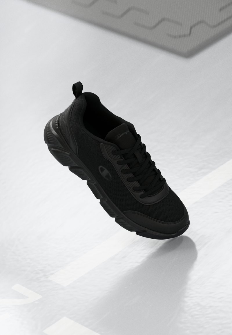 Black athletic shoe featuring mesh material, lace-up design, textured sole, and logo detail on the side. Appears lightweight and flexible.