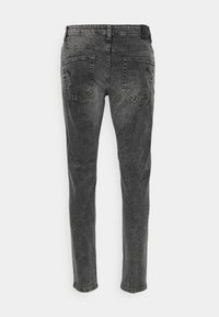 Jeans ajustados de corte slim en negro deslavado con dos bolsillos traseros y pasadores para cinturón, mostrados desde la parte trasera sobre un fondo liso.