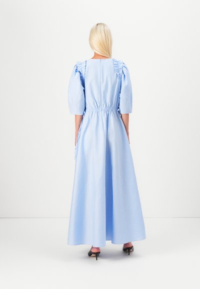 Rochie maxi albastră cu mâneci bufante, talie strânsă și accente volăturate. Confecționată dintr-un material ușor, prezintă o textură fină și o siluetă elegantă.