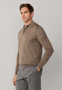 Bruine lange mouwen polohemden met een kraag, drie knopen en een gestructureerde stof, gecombineerd met grijze broek. Aangesloten ontwerp, casual stijl.