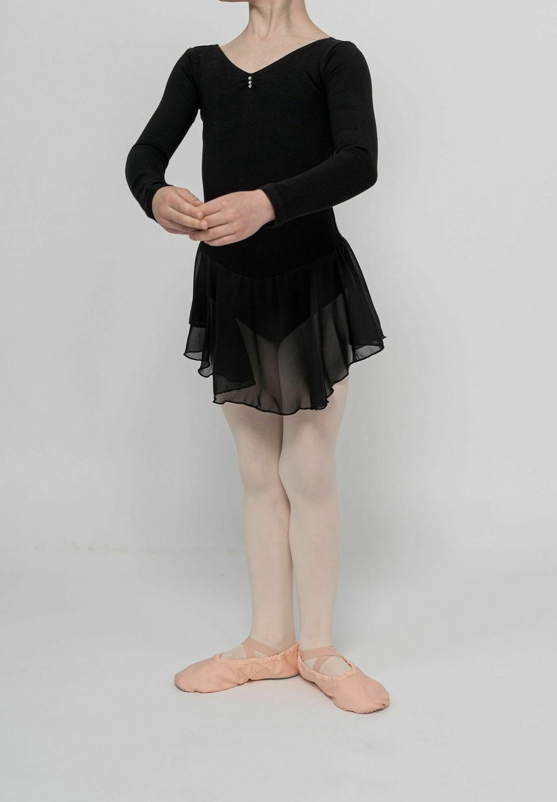 Enfant en tenue de ballet noire et chaussons roses debout en première position, les mains doucement jointes au niveau de la taille.