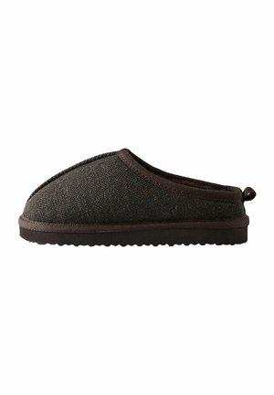 Chausson en tissu marron foncé à enfiler avec semelle texturée et petite boucle au talon, conçu pour le confort intérieur.