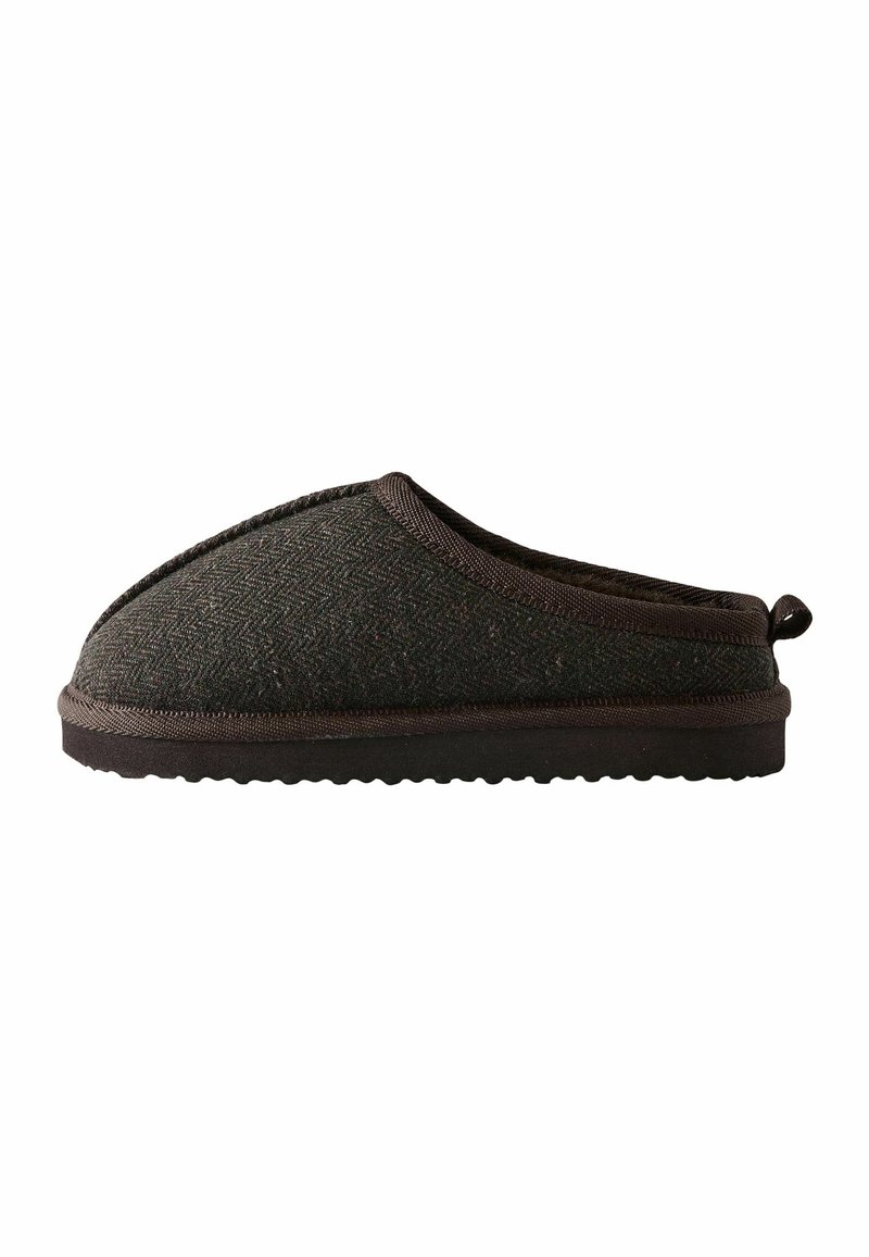 Chausson en tissu marron foncé à enfiler avec semelle texturée et petite boucle au talon, conçu pour le confort intérieur.