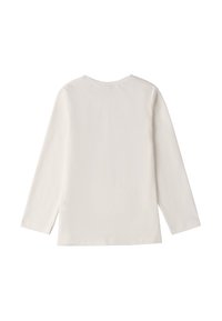 Długi rękaw bluzki w jasnym beżu, wykonanej z miękkiego materiału, z prostym wzorem, okrągłym dekoltem i prostym dołem.