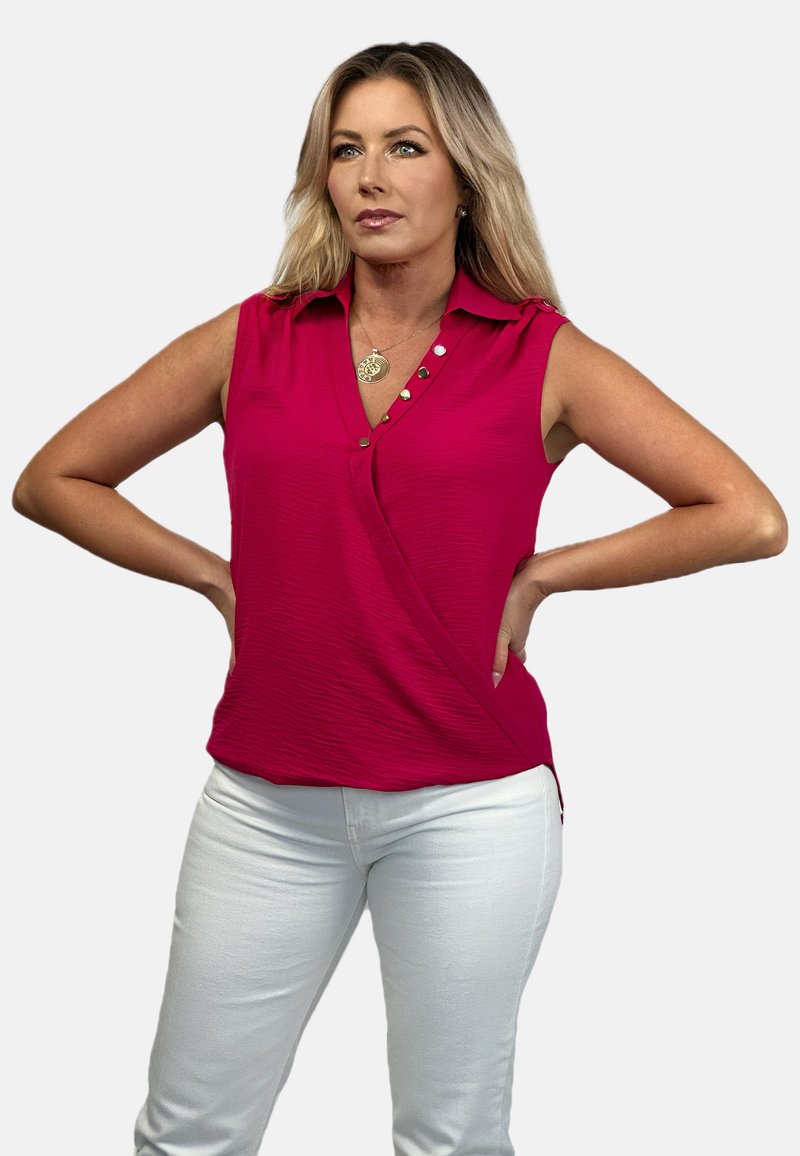 Fuksjowy bezrękawnik z kołnierzykiem, z krzyżującym się przodem, dekoracyjnymi guzikami i teksturowanym materiałem. Połączony z białymi dżinsami.