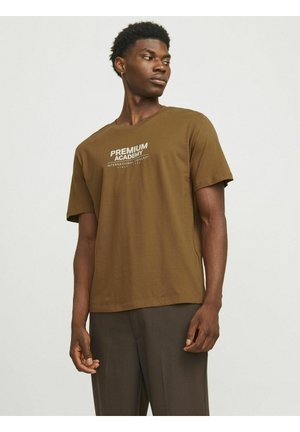 Brun bomulds T-shirt med korte ærmer, der har hvid tekst "PREMIUM ACADEMY" og "INTERNATIONAL CONCEPT" på forsiden. Basis rund halsudskæring.