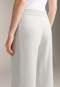 Hellgraue weit geschnittene Hose mit einem gerippten Bund, die eine weiche Textur und vertikale Nahtdetails an den Seiten aufweist.
