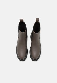 Paire de bottines Chelsea en cuir marron avec panneaux élastiques noirs sur les côtés et languettes à tirer, vues de dessus sur un fond blanc.
