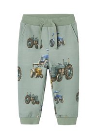 Pantaloni da tuta verdi con stampa di trattori in vari colori, elastico in vita e sui polsini, realizzati in materiale morbido e stretch.
