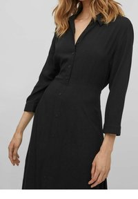 Černé šaty na knoflíky s límcem, dlouhými rukávy a volným střihem. Hladká textura a přizpůsobený design s polodlouhým střihem.