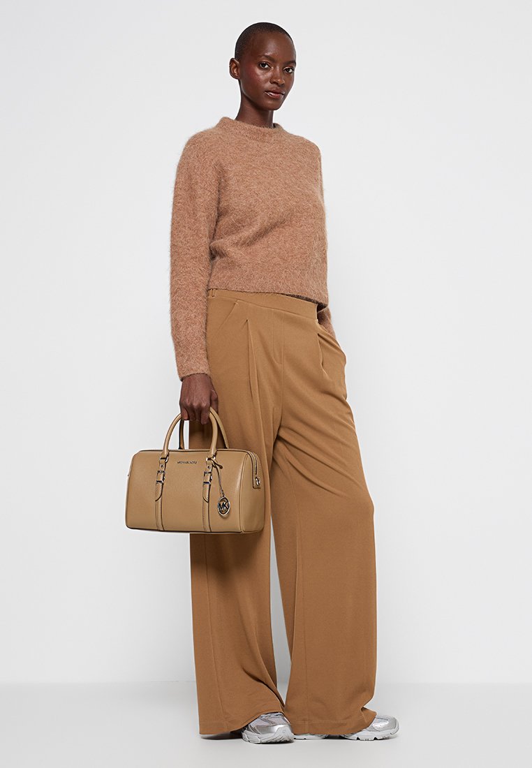 Sac en cuir lisse tan avec anses doubles, quincaillerie dorée et un charm. Associé à un pull tan confortable et un pantalon large tan.