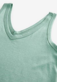 Hele roheline tank top v-kaelusega, mis on valmistatud pehmest kangast. Sellel on puhas viimistlus servadel ja sile, mati tekstuur.