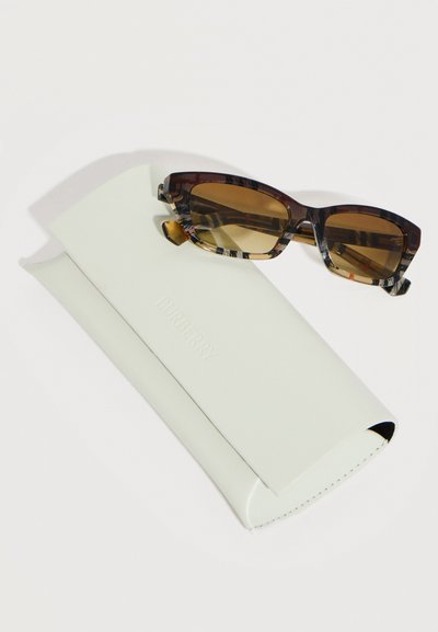Καφέ ορθογώνια γυαλιά ηλίου με κορνίζες από χελωνόκρατο, τοποθετημένα πάνω σε μια λευκή δερμάτινη θήκη με το λογότυπο Burberry.
