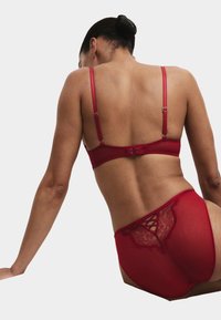 Rødt lingerisæt med en bh med justerbare stropper og et matchende par højtaljede trusser med blondeaccenter og en gennemsigtig finish.