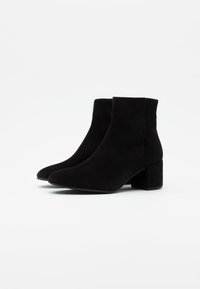 Botines de ante negros con tacón cuadrado, punta afilada y textura suave. Diseño sencillo sin herrajes o patrones visibles.