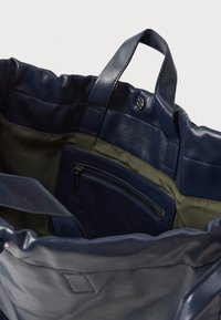 Mere nahk tote kott rohelise kangas sisuga, millel on sisemine tõmbluku tasku ja lühikesed sangad.