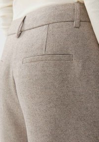 Šedé kalhoty s texturou a jemným vzorem. Obsahují dvě zadní kapsy a hladký pas. Materiál vypadá tkaný a upravený.