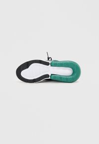 Czarna i zielona podeszwa sneakersa z teksturowaną gumą, białą środkową częścią podeszwy oraz segmentowanym wzorem zapewniającym przyczepność.