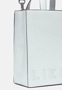 Weiße Lederhandtasche mit einer strukturierten Form. Sie verfügt über geprägte Buchstaben und schwarze Kanten. Enthält kurze Griffe und eine silberne Hardware-Akzent.
