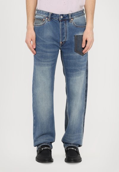 Denim Jeans in Hellblau mit lässiger Passform, ausgestattet mit einer kontrastierenden dunkelblauen Aufsetztasche und dezenten Ausbleichungen entlang der Beine.